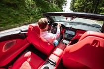 Maserati GranCabrio Trofeo review: interior driving shot, Piers Ward at the wheel, high angle, red leather upholstery