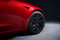 Tesla Model 3 Performance: alloy wheel detail shot, red paint, studio shoot