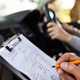 Driving test, examiner with clipboard in passenger seat