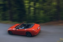 Maserati GranCabrio Folgore review: rear three quarter driving through forest, orange paint