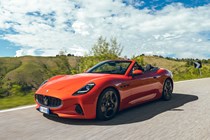 Maserati GranCabrio Folgore review: front three quarter driving through brushland, orange paint