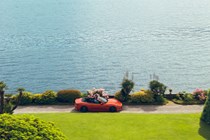 Maserati GranCabrio Folgore review: side view driving next to lake, orange paint