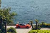 Maserati GranCabrio Folgore review: side view driving along lakeside, orange paint