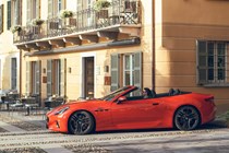 Maserati GranCabrio Folgore review: side view driving through city, orange paint