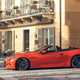 Maserati GranCabrio Folgore review: side view driving through city, orange paint