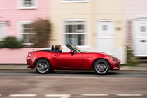 Mazda MX-5 review - side view, red, roof down, driving through town