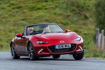 Mazda MX-5 ND review - front view, red, roof down, driving round corner