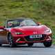 Mazda MX-5 ND review - front view, red, roof down, driving round corner