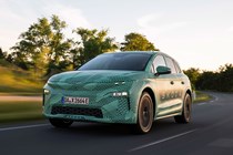 Skoda Elroq prototype: front three quarter driving, on a country road, sunset, green camo wrap