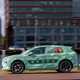 Skoda Elroq prototype: side view driving, in a city, sunshine, green camo wrap