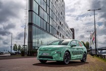 Skoda Elroq prototype: front three quarter static, green camo wrap, building in background