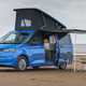 Image of a blue Volkswagen California at the beach with its pop-top up | Parkers cars
