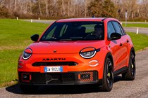 Abarth 600e (2024) review: front three quarter driving, orange paint