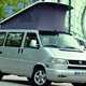 Image of Volkswagen T4 camper van in silver, front right three-quarters view with raised pop-top