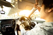 Image of a woman shielding her eyes while driving into very bright sunlight