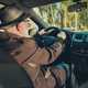 Image of a man wearing a trilby hat while driving