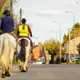 Image of a pair of horses with riders walking along a road