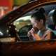 Image of a woman eating while in the drivers seat of a car