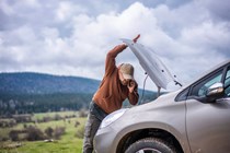 Image of a man opening the bonnet of a broken down Nissan