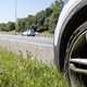 Image of a broken down car on a motorway shoulder, close-up showing the front wheel and looking down the carriageway