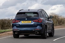 BMW X3 review (2023): rear cornering shot, showing body roll, blue car, rural background