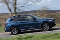 BMW X3 review (2023): driver's side pan shot, blue car, rural background