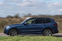 BMW X3 review (2023): passenger side pan shot, blue car, rural background