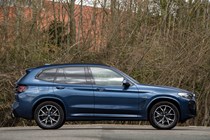 BMW X3 review (2023): side view static, blue car, wooded background