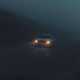 Image of a dimly lit Mercedes C-Class driving through fog