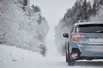 Image of a Subaru Crosstrek driving along a snowy, hilly road