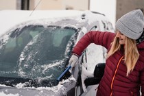 Image of a woman clearing snow off a car