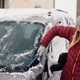 Image of a woman clearing snow off a car