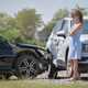 Image of a young woman standing between two crashed cars