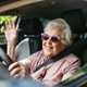 Image of a happy elderly woman behind a car's steering wheel