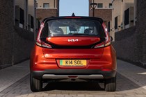 Kia Soul EV (2023): rear static, orange paint, buildings in background