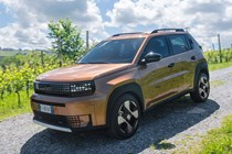 Fiat Grande Panda Hybrid (2025) review: front three quarter driving, gravel road, bronze paint