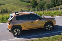 Fiat Grande Panda Hybrid (2025) review: side view driving, bronze paint, high angle