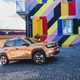 Fiat Grande Panda Hybrid (2025) review: front three quarter cornering, bronze paint, colourful house in background