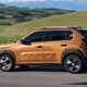 Fiat Grande Panda Hybrid (2025) review: side view driving, bronze paint, hills in background