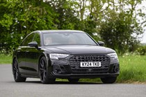 Image of a black Audi S8 driving around a corner, looking at its front right corner