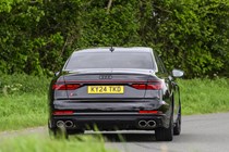 Image of a black Audi S8 driving around a corner, looking at its rear end
