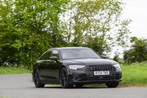 Image of a black Audi S8 driving around a corner, looking at its front right corner