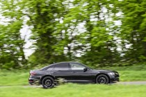 Image of a black Audi S8 driving around a corner, looking at its right side