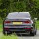 Image of a black Audi S8 driving around a corner, looking at its rear end