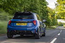 Image of a blue MINI JCW hatchback driving, viewed from the rear