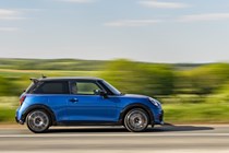 Image of a blue MINI JCW hatchback driving, viewed from the right side