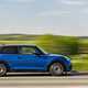 Image of a blue MINI JCW hatchback driving, viewed from the right side