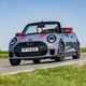 Image of a grey MINI JCW convertible driving round a corner, viewed from the front