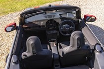 Image of an MINI JCW's convertible interior with the hood folded, looking forward from the rear, from a high view-point