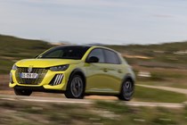 Peugeot E-208 review - facelift, front view, driving round corner, yellow